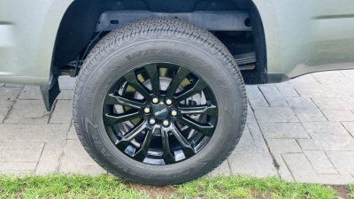 GMC Canyon wheel and tire close-up showing black multi-spoke alloy rim and rugged tire under fender.