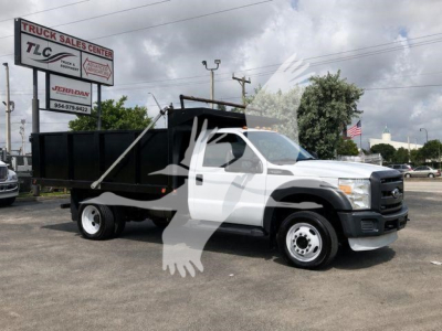 Ford F-450 dump truck in serviceable condition with white cab and black dump bed, showing front grille and side profile.