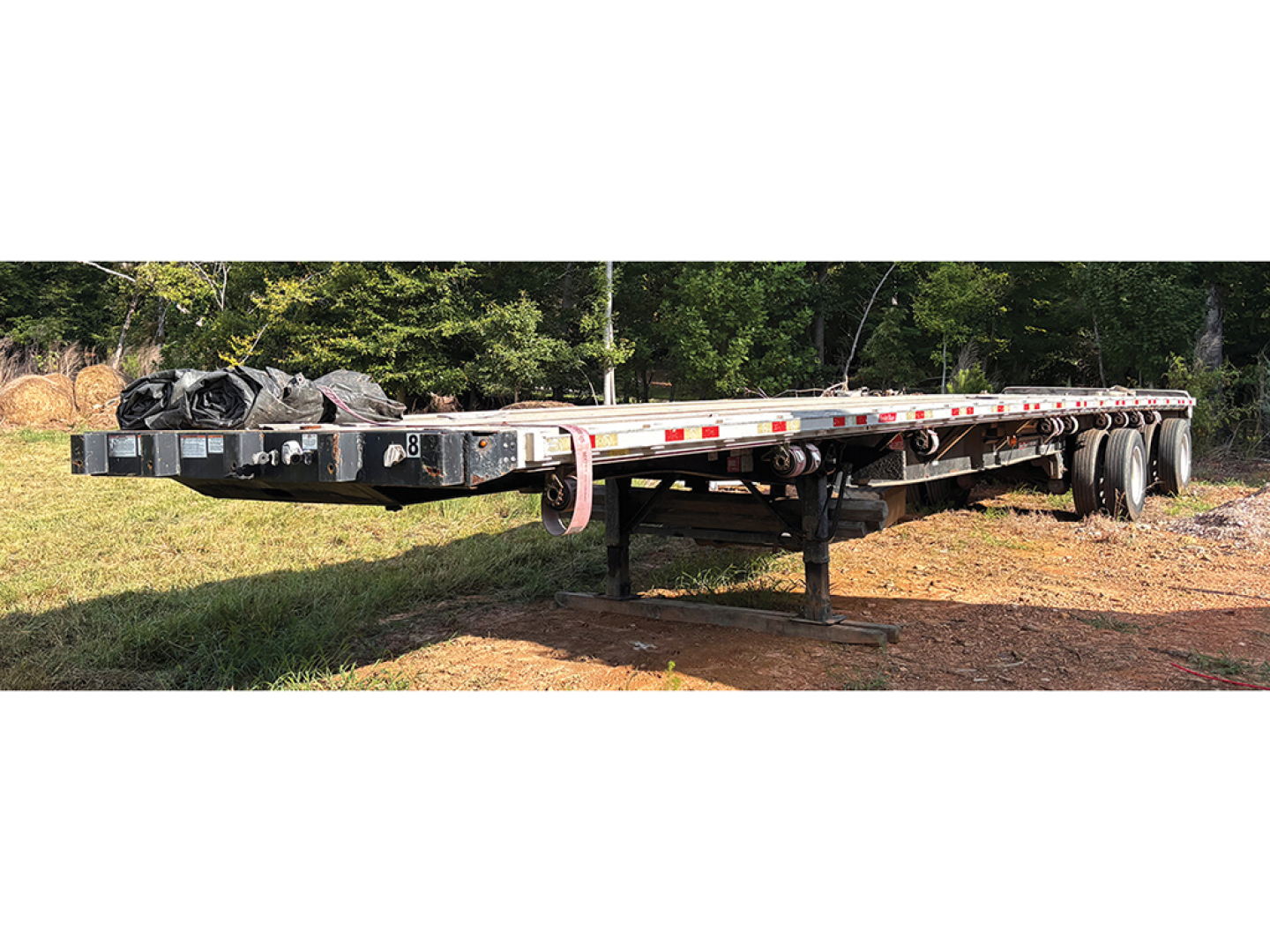 Great Dane aluminum and steel composite flatbed trailer, side view showing long deck, tandem axles, and undercarriage with support legs.