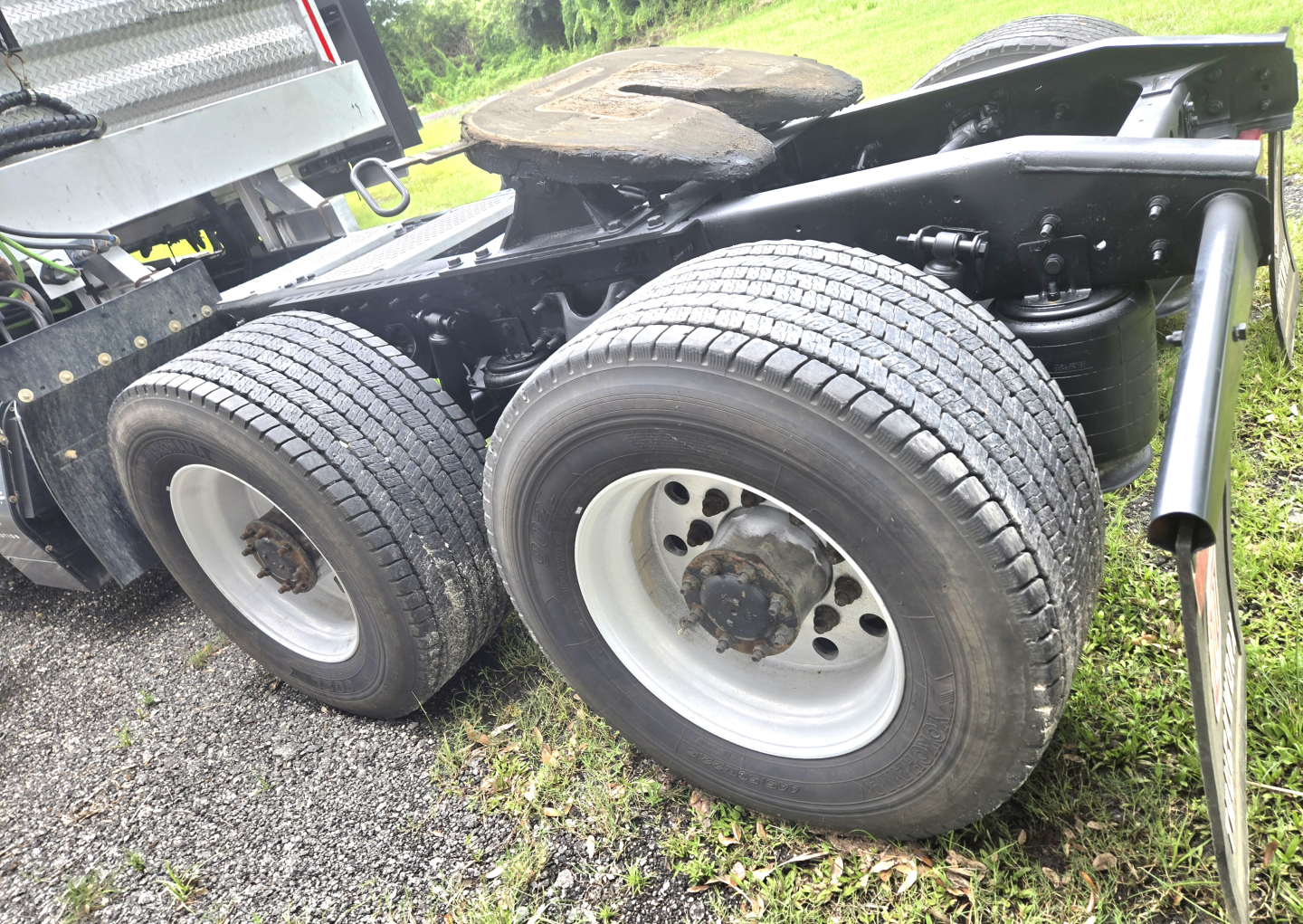 Dual rear tractor-trailer wheels and suspension of a 2019 International LT625 Condo truck showing axles and tire tread.