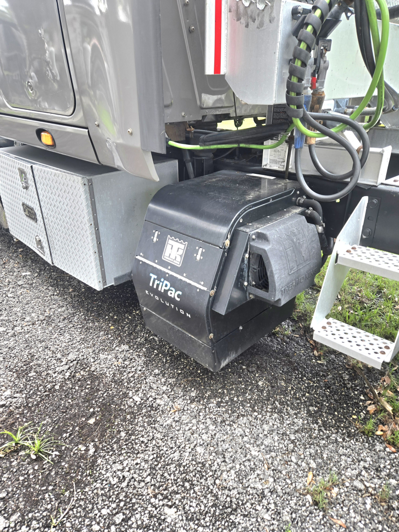Condo truck undercarriage showing Tripac Evolution battery/air system housing labeled Tripac Evolution and various hoses and wiring near a metal toolbox.