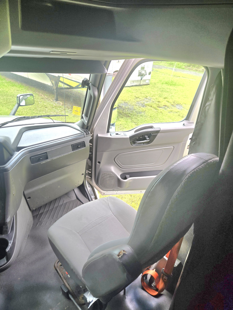Cab interior of a 2019 International LT625 Condo truck showing front seats, dashboard, and open passenger door.
