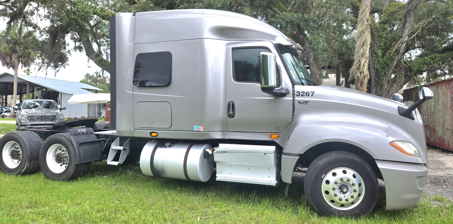 Truck cab side view of a silver 2019 International LT625 Condo with 6-wheel chassis and fuel tanks, showing window, door, and side mirror.