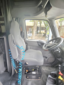 Interior cab of a used 2019 International LT625 Condo truck showing driver seat with blue coiled air hose and dashboard area