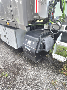 Condo truck undercarriage showing Tripac Evolution battery/air system housing labeled Tripac Evolution and various hoses and wiring near a metal toolbox.