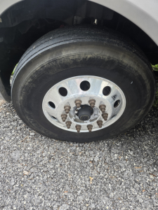 Truck wheel and tire assembly showing lug nuts and steel rim on a 2019 International LT625 condo sleeper.
