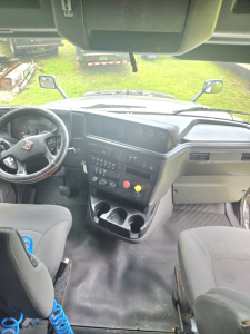 Interior of a 2019 International LT625 condo sleeper truck cab showing steering wheel dashboard controls and center console with gauges and cup holders.