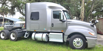 Truck cab side view of a silver 2019 International LT625 Condo with 6-wheel chassis and fuel tanks, showing window, door, and side mirror.