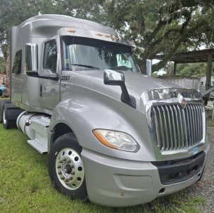 Truck cab showing International LT625 sleeper with chrome grille and side mirrors, silver exterior, numbers 13267 on door, large front bumper and wheel.