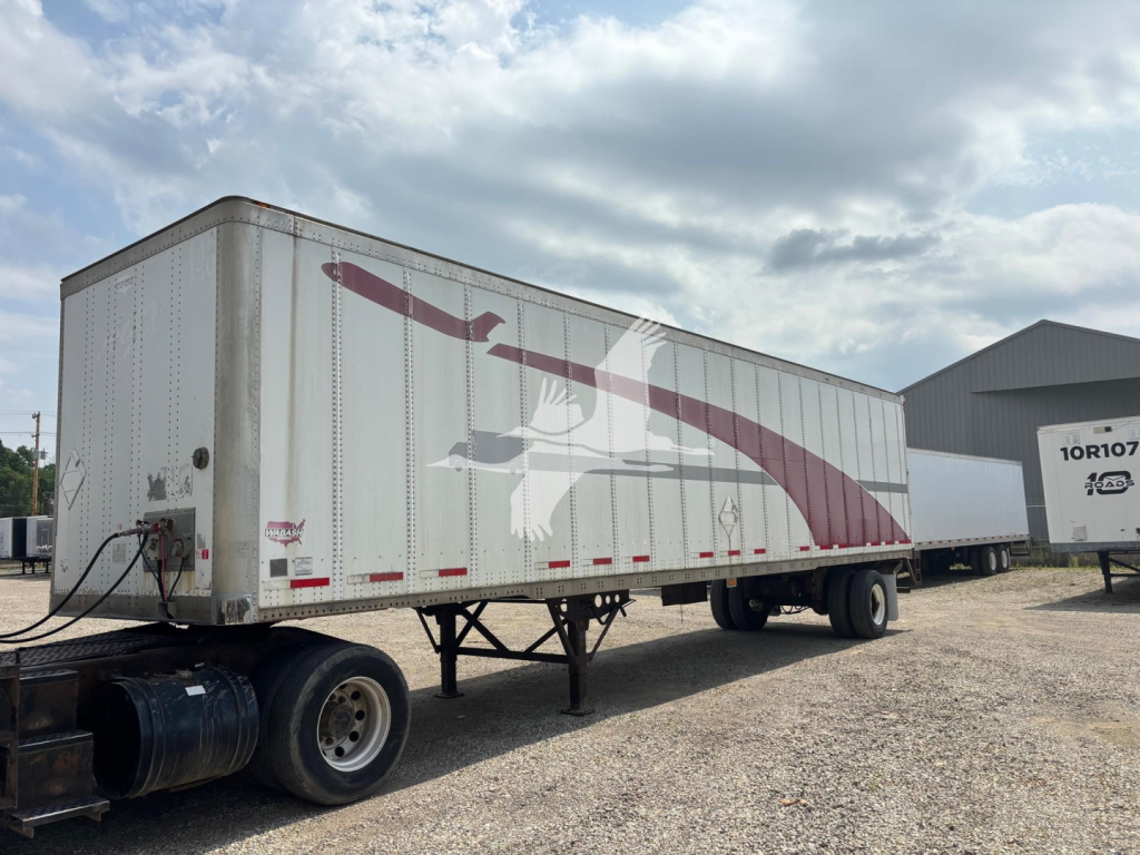 Trailer side showing large graphic artwork with maroon swoosh and bird on a white Wabash trailer, tandem axles, in a lot.