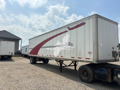 Trailer side panel with graphic design showing bird emblem and curved maroon graphics on white background.