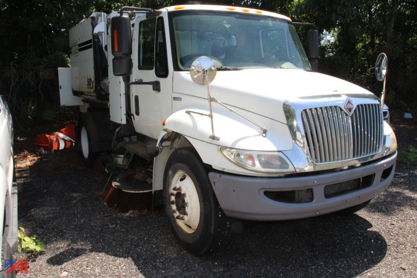 Front-left view of a white 2010 International DuraStar 4300 Tymco Sweeper truck with side cab mirrors and sweeping equipment visible.