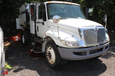 Front-left view of a white 2010 International DuraStar 4300 Tymco Sweeper truck with side cab mirrors and sweeping equipment visible.