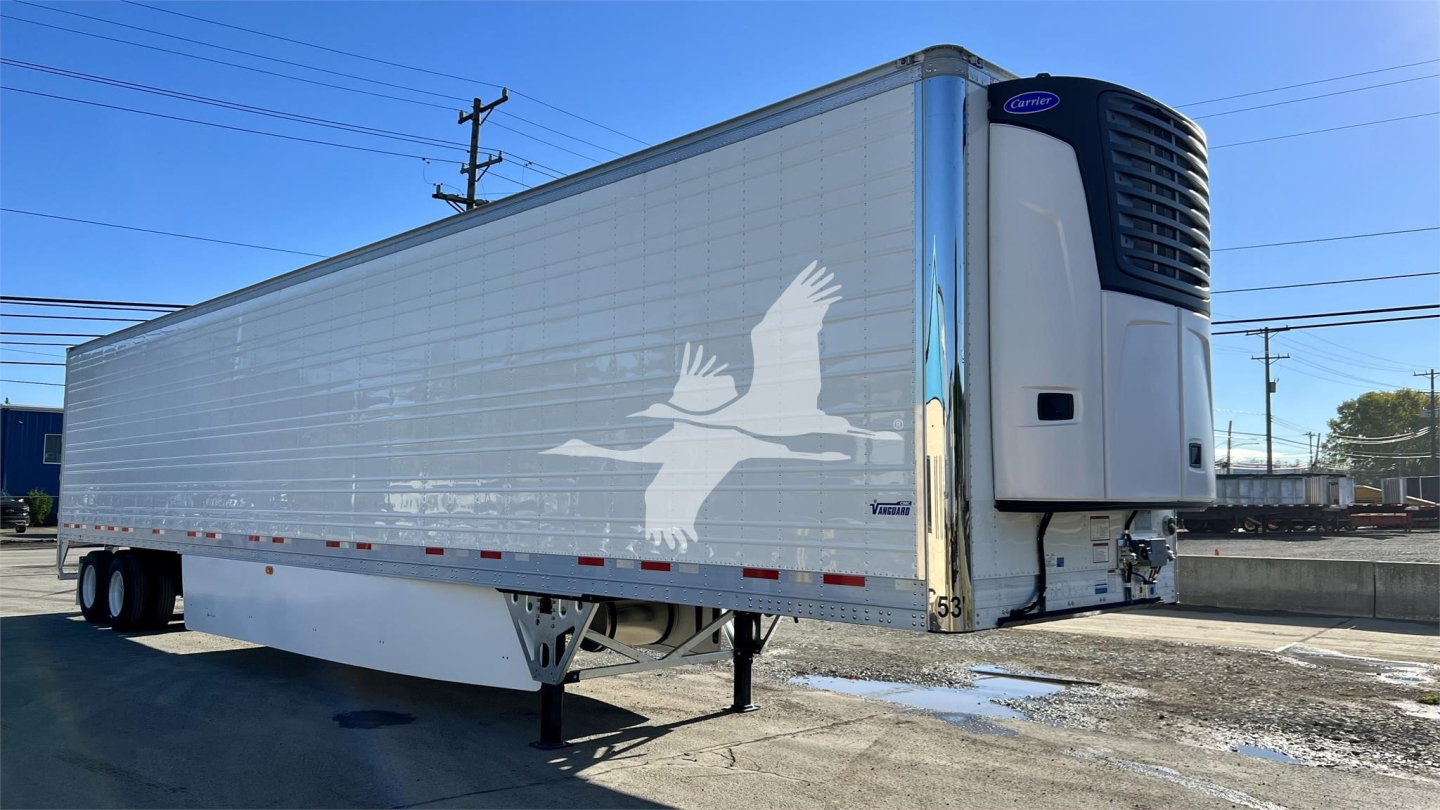 Reefer trailer showing Vanguard Cool Globe with white dove graphic on side and front refrigeration unit, side view, parked outdoors.