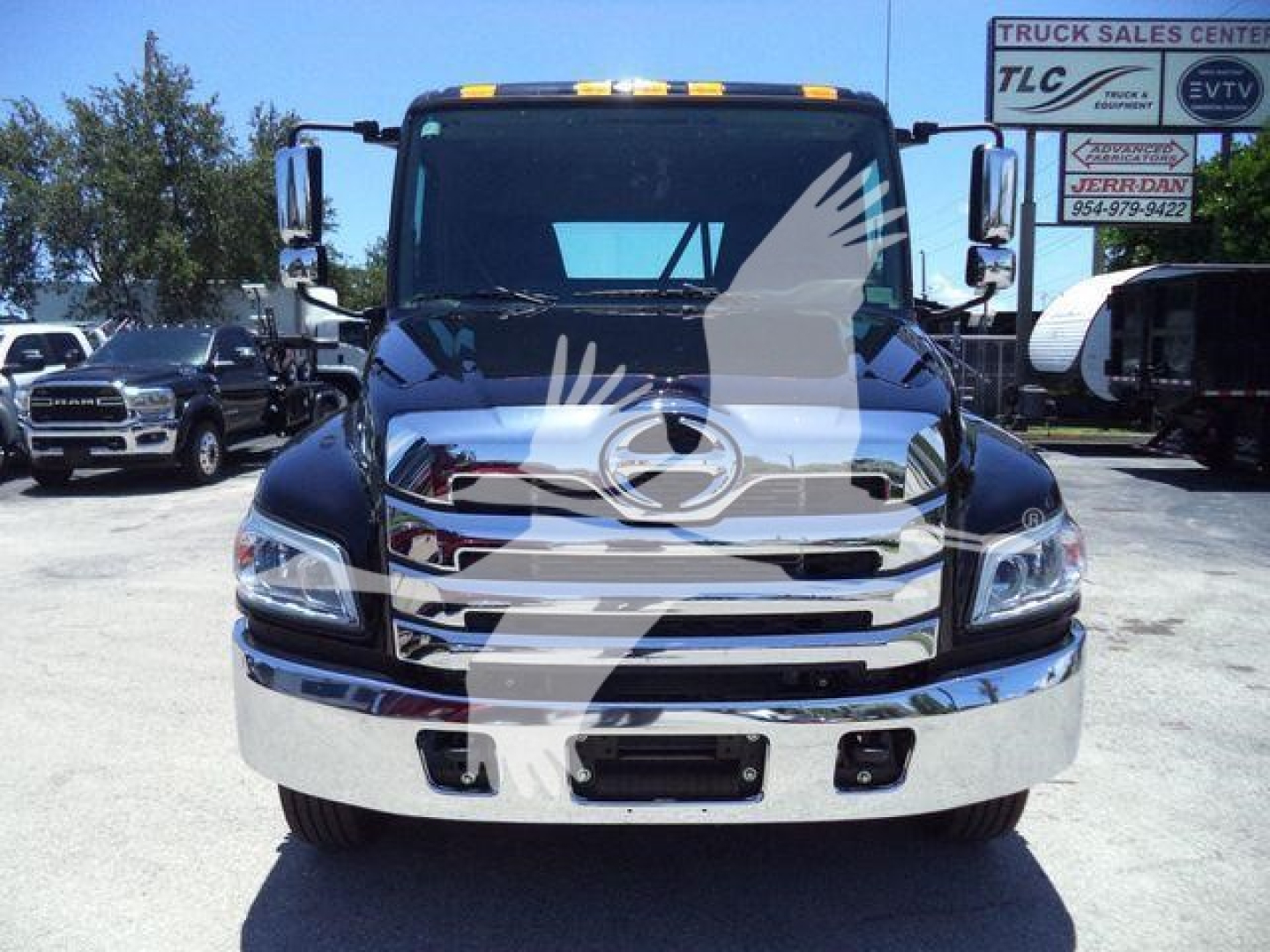 Front view of a black 2026 Hino L6 truck showing chrome grille, bumper, and headlights in a dealership lot.