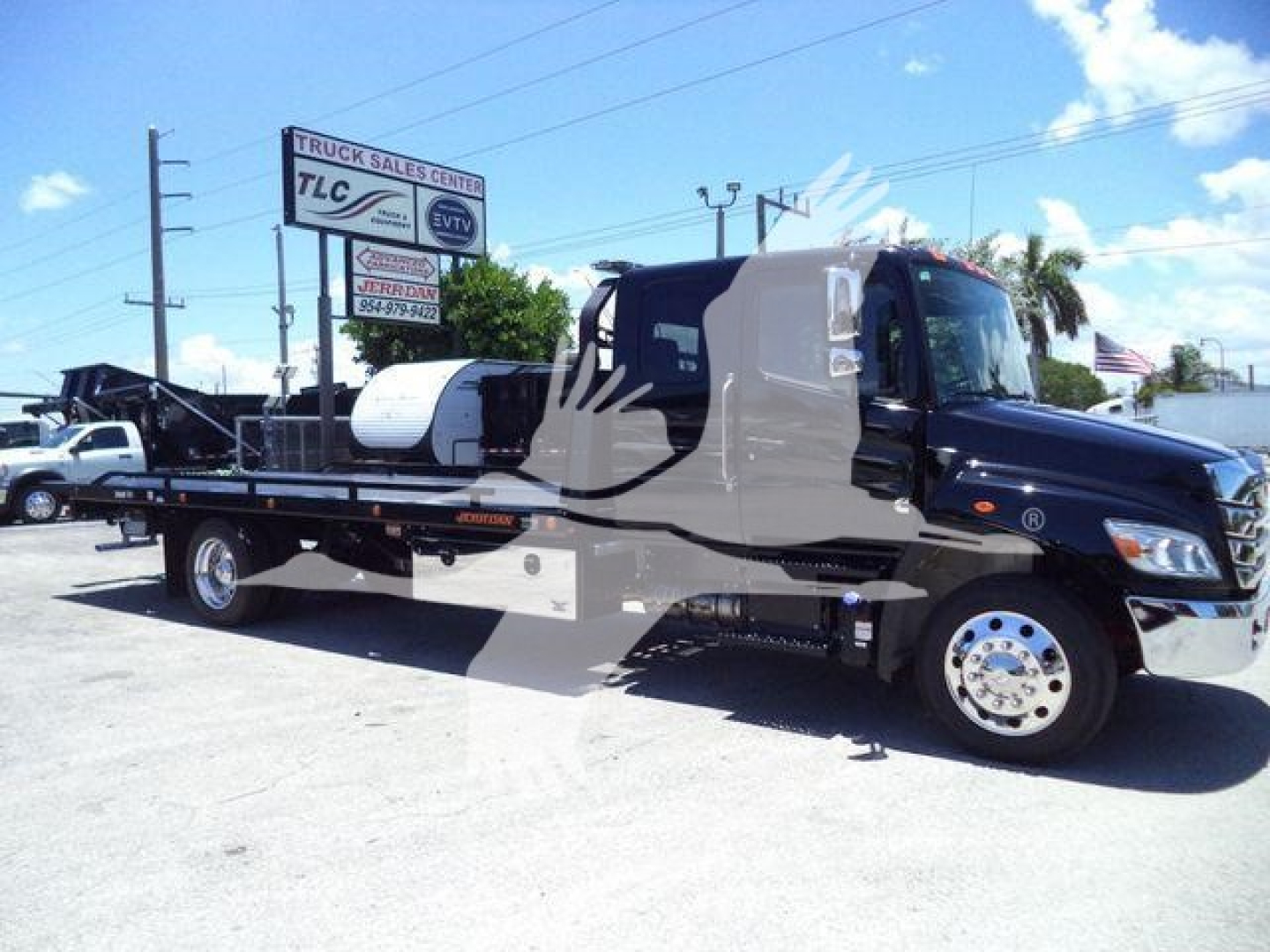 Truck bed rollback truck with flatbed and crane on a 2026 Hino L6 chassis, side view parked at a dealership.