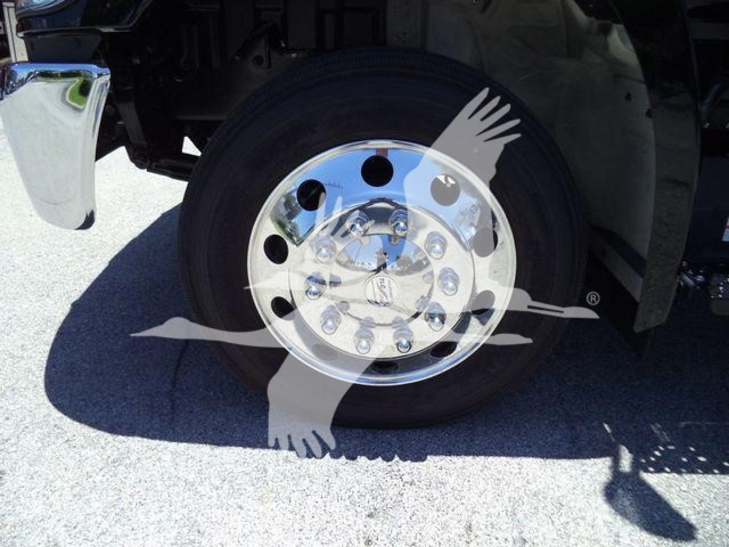 Truck wheel and front fender showing chrome wheel with lug nuts and hubcap; rubber tire; undercarriage and wheel well visible.