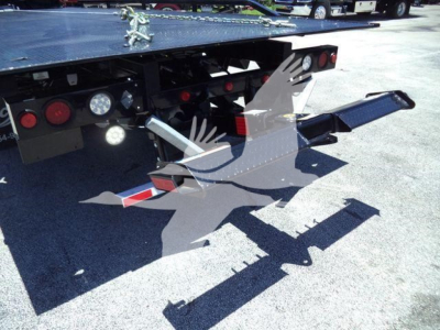 Back of a rollback tow truck showing mounted wheel-lift arms and hydraulic components with reflectors and taillights.
