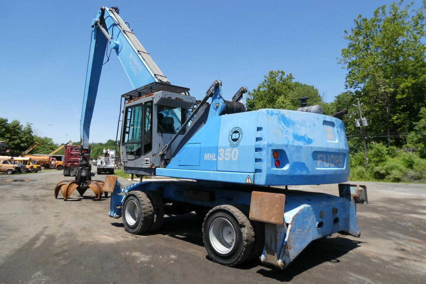 Terex MHL350D hydraulic crane in blue showing rear and side, with MHL350 label on cab and FUCHS sign, in an outdoor lot.