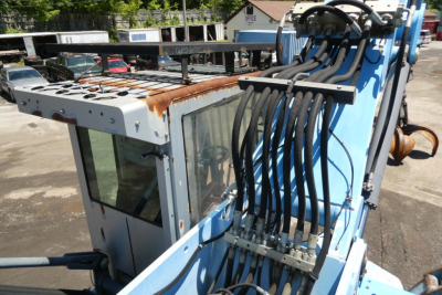 Terex MHL350D boom lift attachment with hydraulic hoses and operator cab in view, shows control hoses and rusted metal surfaces.