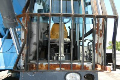 Terex MHL350D front view with protective grille and cabin, metal frame and rust edges visible; operator seat and controls behind bars.