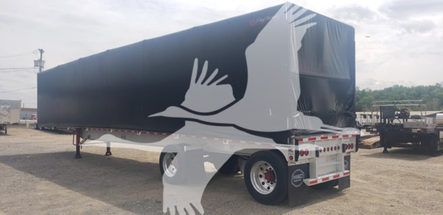 Curtainside trailer in view with black tarp and white silhouette graphic of a bird overlaying the side. Dual-axle trailer with landing gear visible; rear bumper and lights present.
