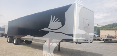 Curtainside trailer with blue side panel showing white silhouette graphics of a bird; front and rear details visible; no legible small text.