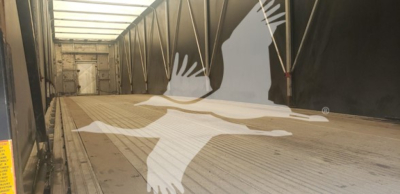 Trailer interior showing a bare wooden deck with side rails and a large graphic of a flying bird across the floor.