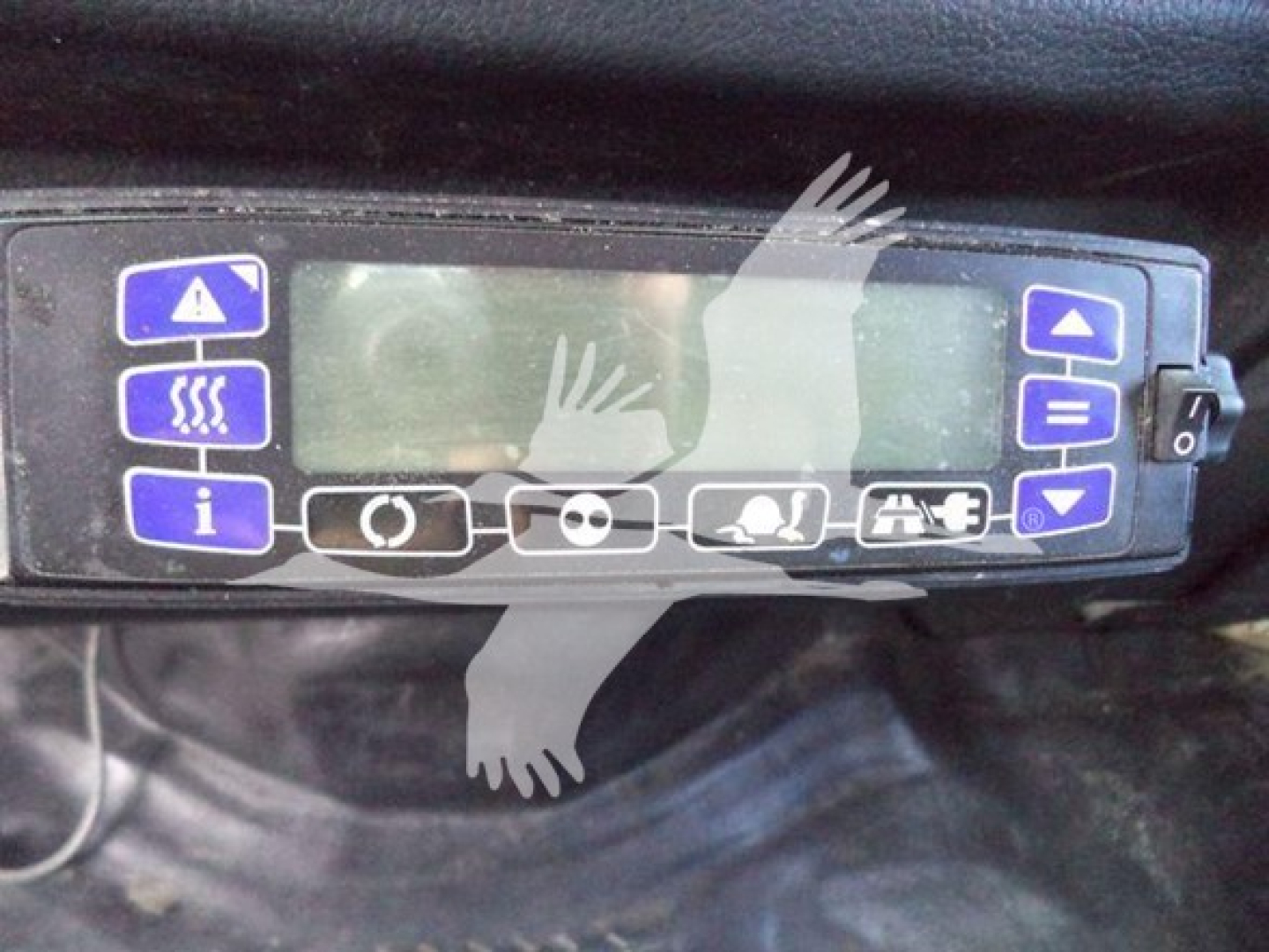 Truck cab control panel with blue and white buttons and a small LCD display, mounted in a vehicle cabin.