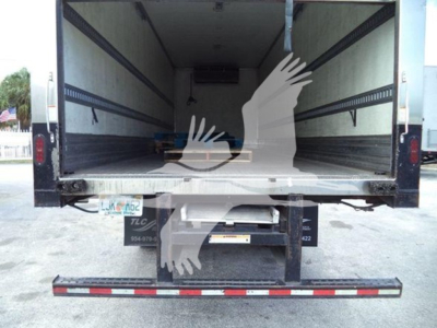 Truck rear view with empty refrigerated bay and liftgate, open doors. Visible text includes VIN-like plate area and stock number partially legible, with reflection of palm watermark.