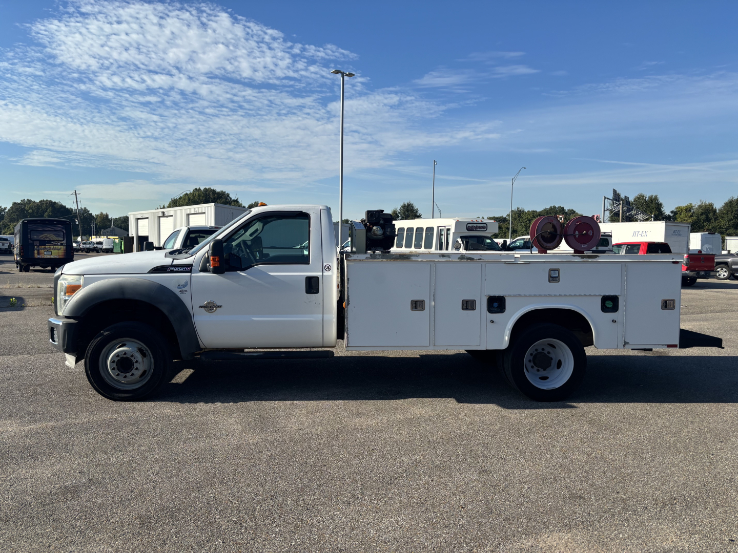Ford F-550 service body truck side view showing utility compartments, hose reels, and service bed with ladder rack.
