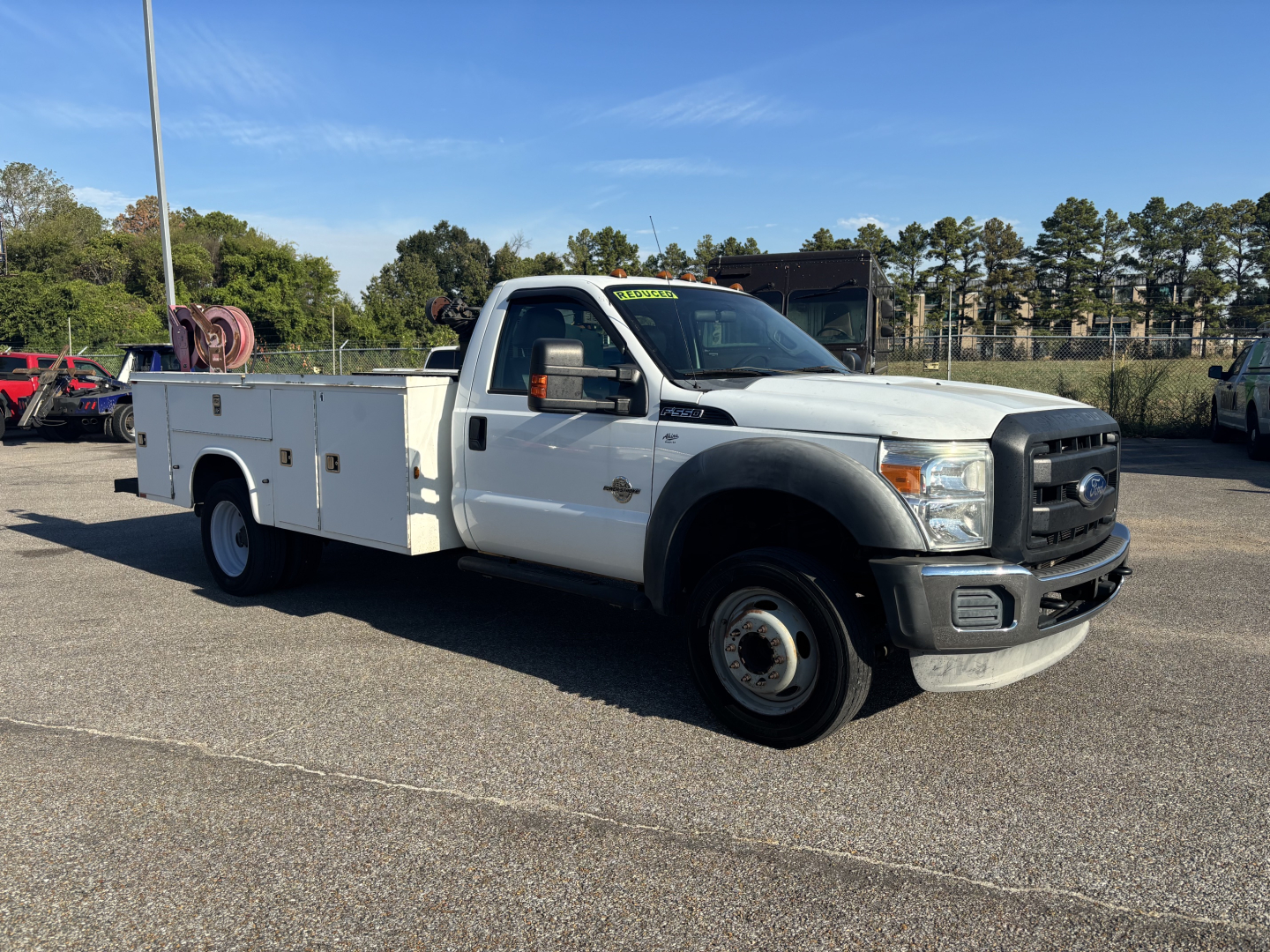 Ford F-550 service utility truck with utility bed and dual rear wheels, white exterior, front grille, headlights, and side mirrors.