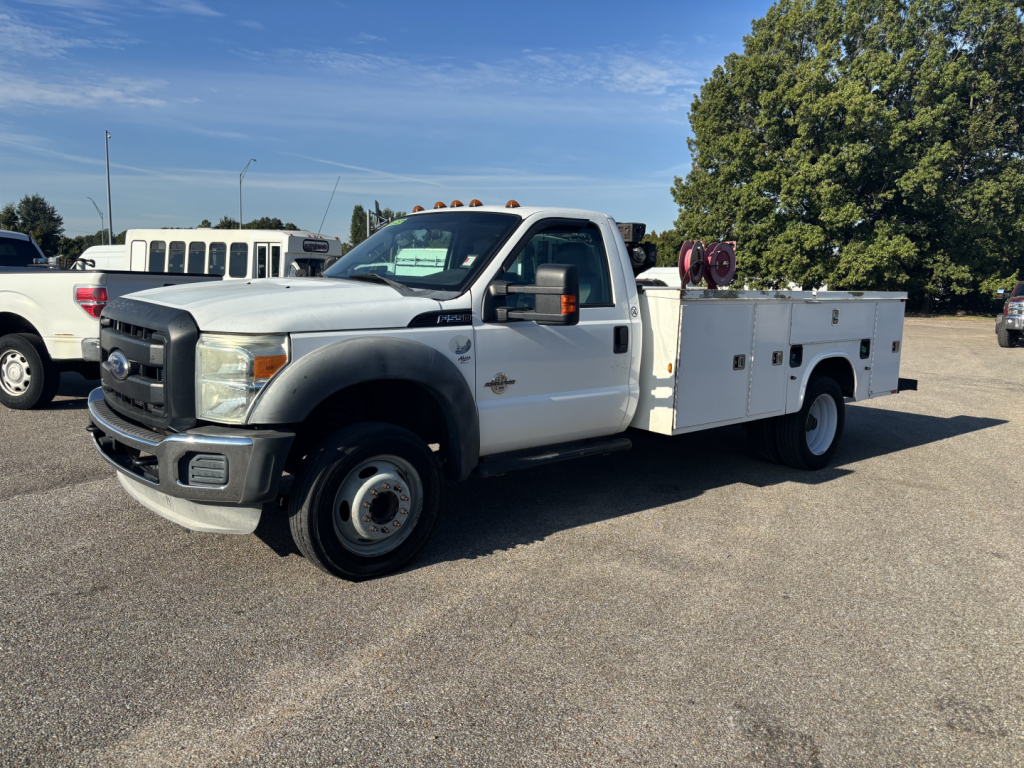 White 2012 Ford F-550 service/utility truck with utility bed and equipment on a sunny day. Side view showing cab, dual rear wheels, and tool compartments. No visible text on body other than standard styling.