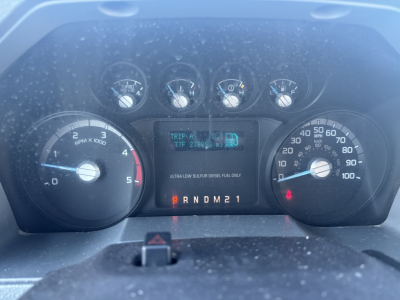 Instrument cluster of a 2012 Ford F-550 dash showing multiple gauges and digital display with transmission gear indicator PRNDM21 and fuel/engine readings.