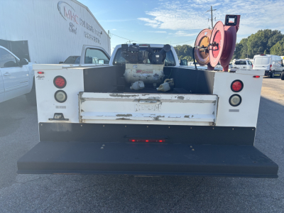 Ford F-550 service truck rear view showing utility bed with storage, fuel tank, and hose reel mounted in bed.