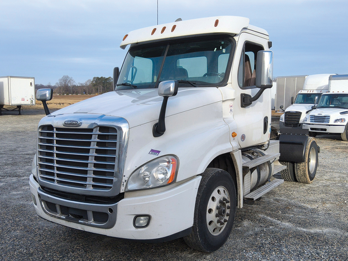 Freightliner Cascadia125 daycab truck in a lot showing front grille and cab mirrors with white exterior.