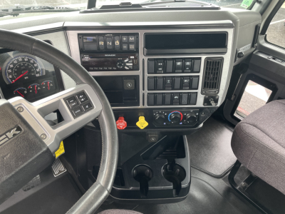 Dashboard and steering wheel of a Mack AN64T daycab showing steering wheel, gauges, climate controls, and center console.