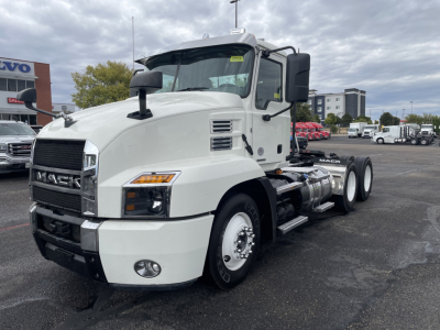 Mack AN64T conventional daycab truck front-left view showing white cab, large grille, dual rear axles, fuel tanks, and side mirrors.