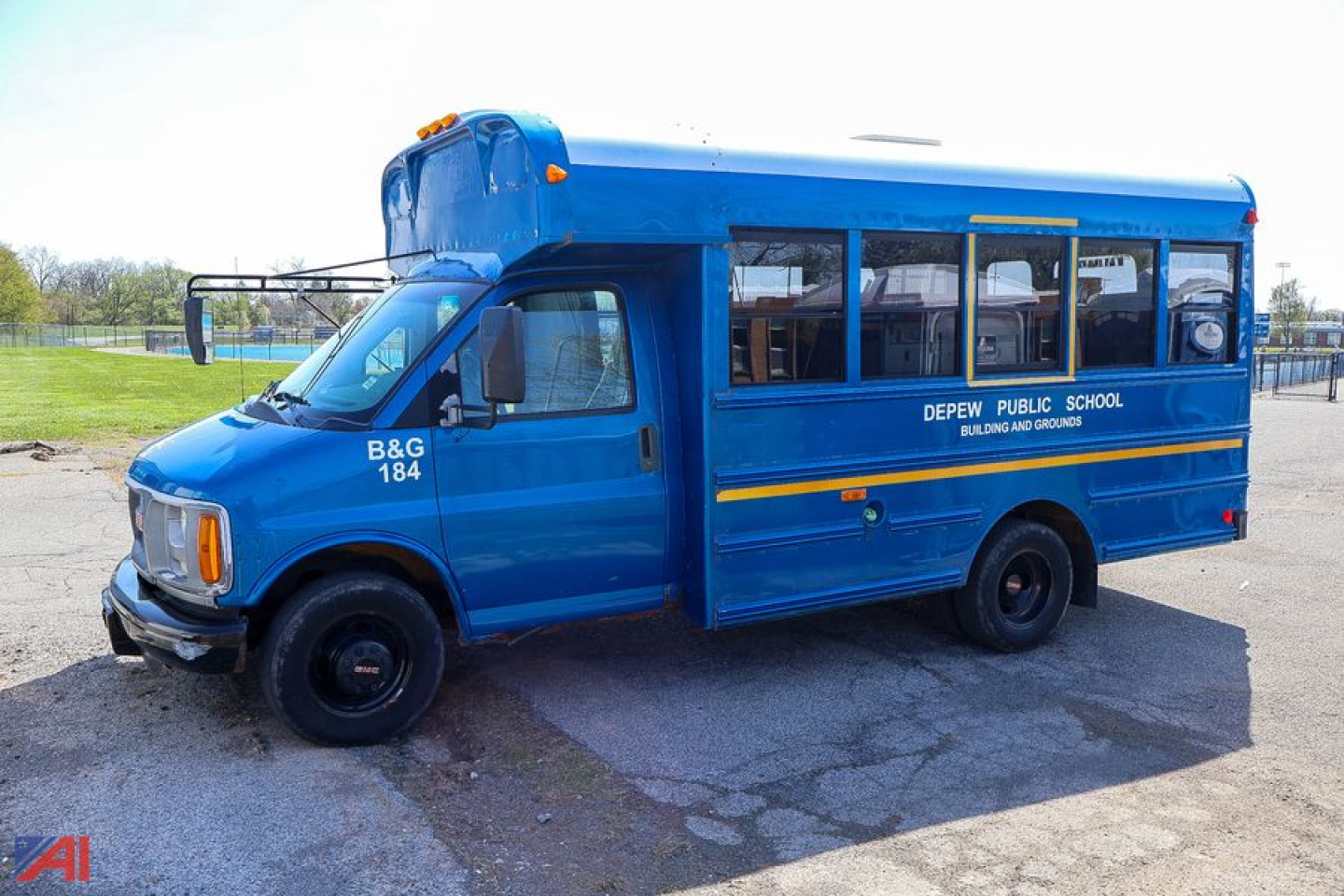 Blue GMC Savana school bus showing B&G 184 on front and Depew Public School text along side, side windows and yellow stripe.