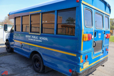 Blue GMC Savana school bus rear and side showing Depew Public School text and yellow stripes.