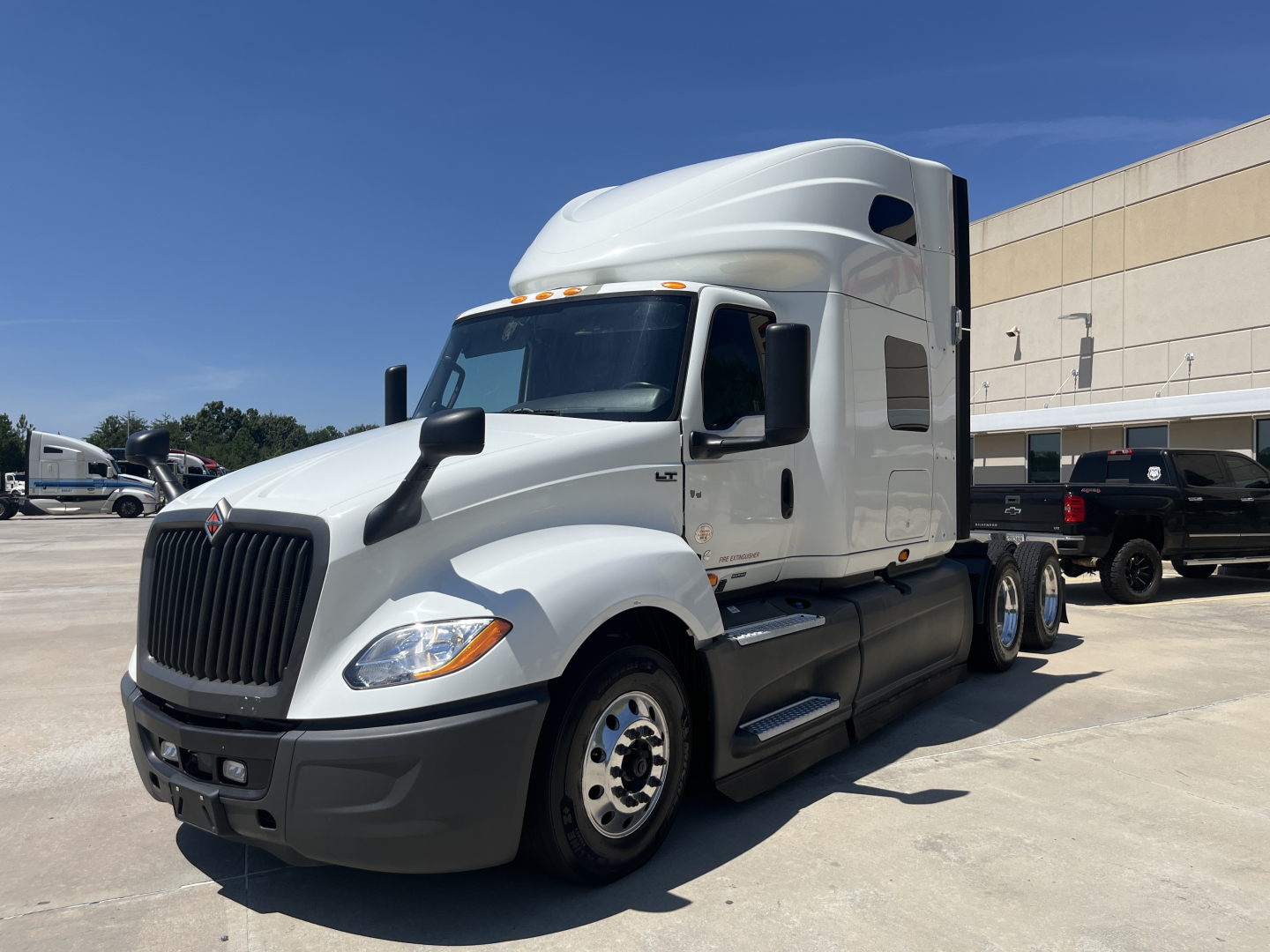 2021 International LT625 truck in a dealership lot showing International grille, aerodynamic sleeper cab, and dual rear axles.