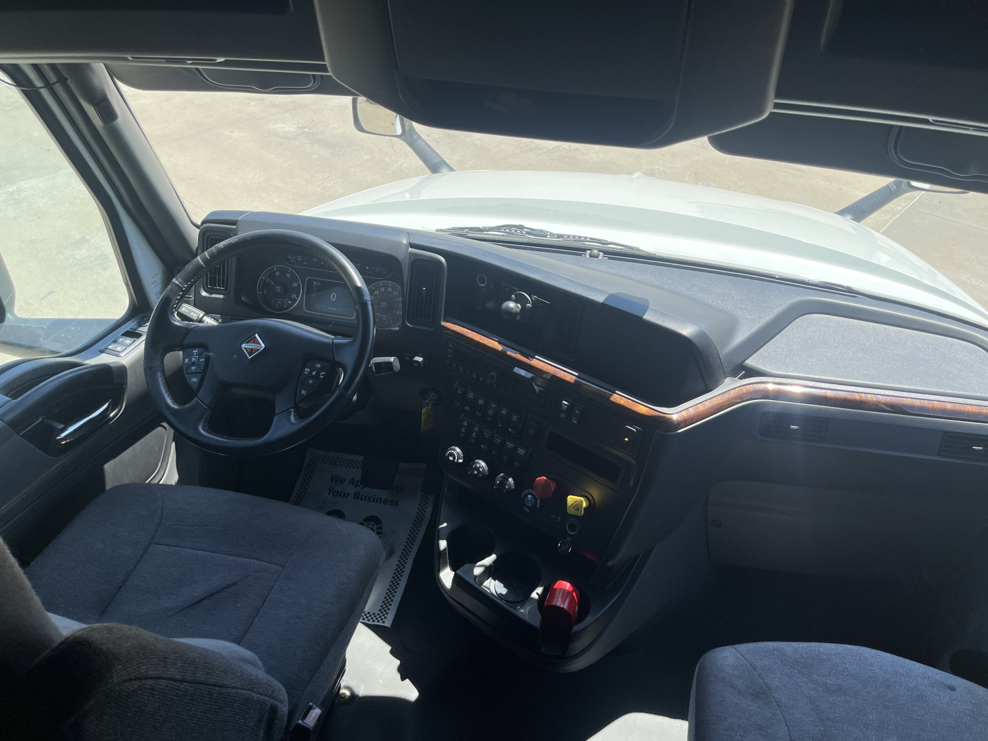 Cab interior of a 2021 International LT625 truck showing steering wheel, dashboard, and center console with controls and wood trim.