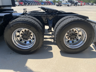 Dual rear axles of a truck chassis with Michelin tires and polished aluminum rims, visible under carriage and frame rails.