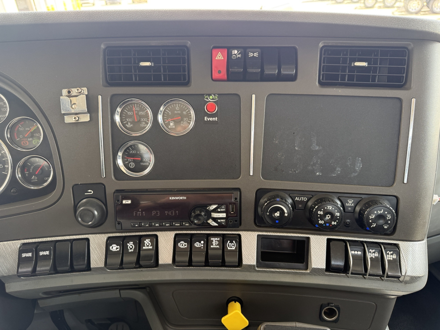 Kenworth T880 dashboard showing instrument cluster, warning switches, vents, and control panel with various gauges and knobs.