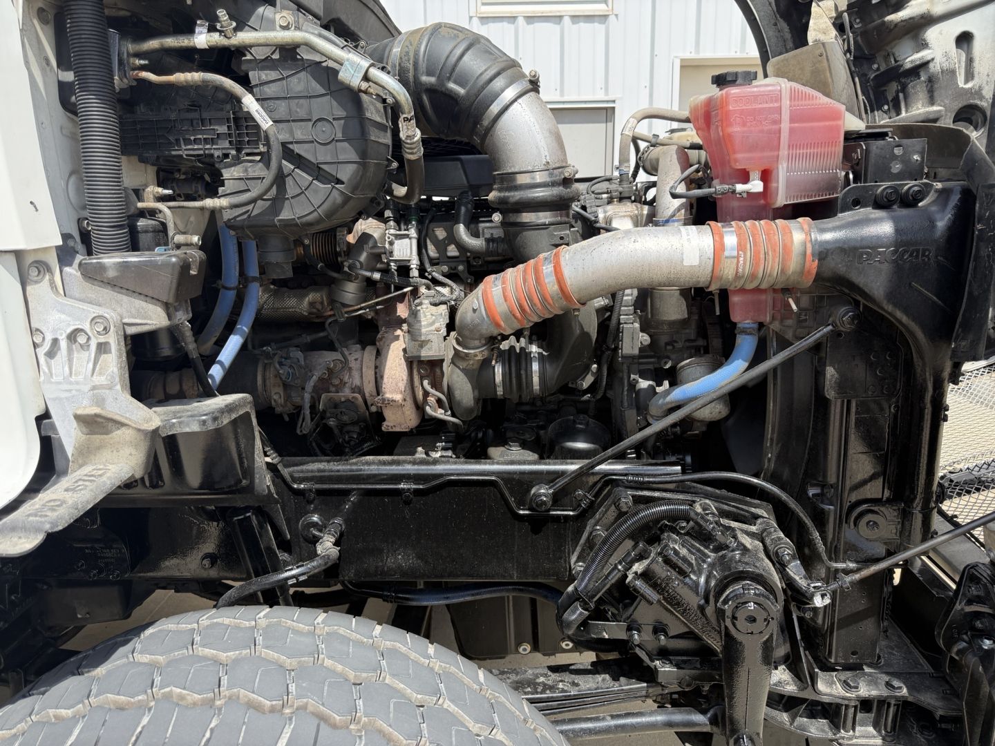 Kenworth T880 engine bay with visible hoses, intercooler, and coolant reservoir.
