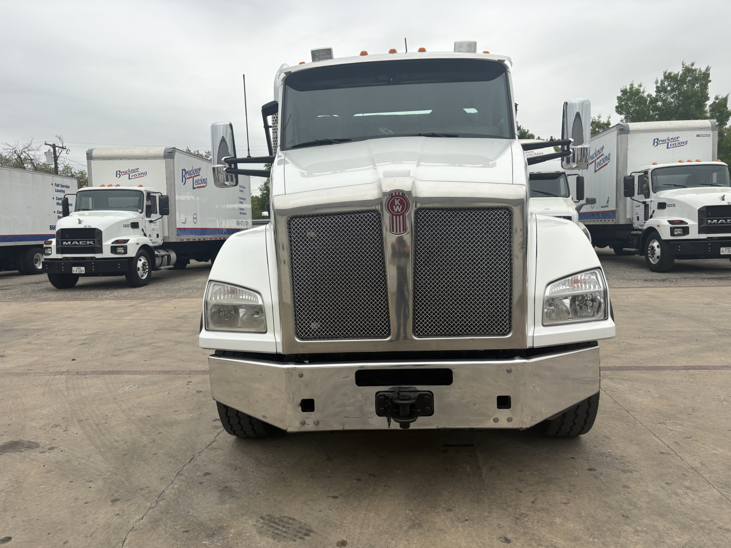 Kenworth T880 front view showing chrome grille, bumper, and headlights in a truck lot.