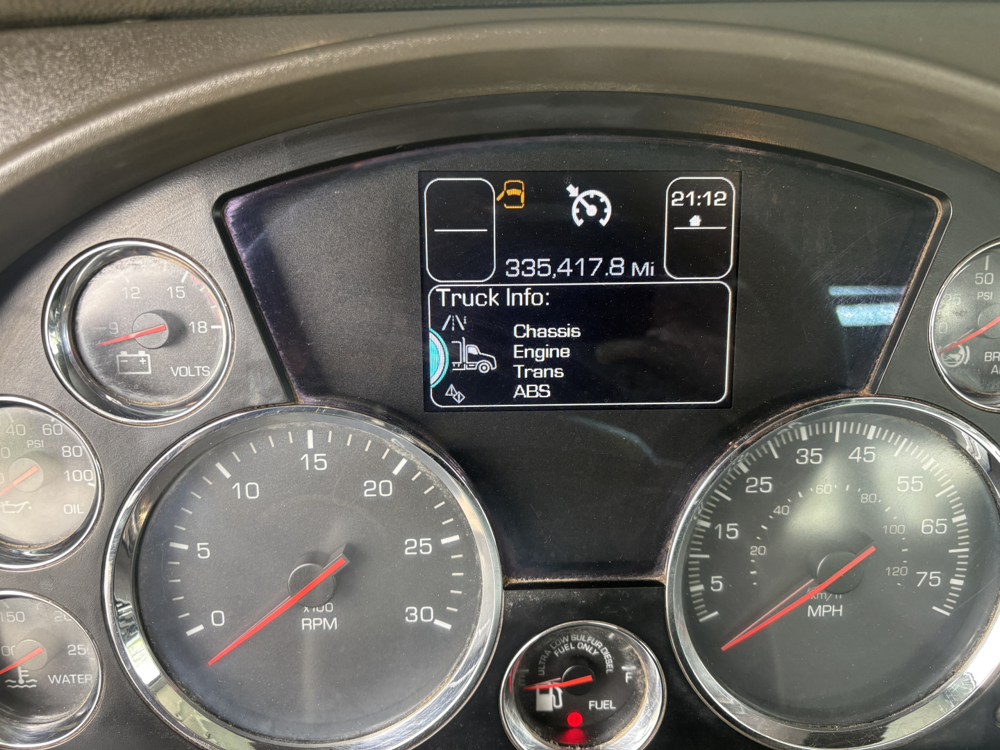 Gauge cluster and digital display of a Kenworth T880 showing engine data, with tachometer and speedometer, and a central screen listing Truck Info: Chassis, Engine, Trans, ABS.