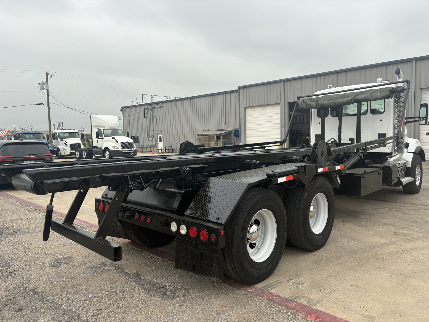 Kenworth T880 roll-off truck rear and side view showing flatbed and rear bumper with lights.