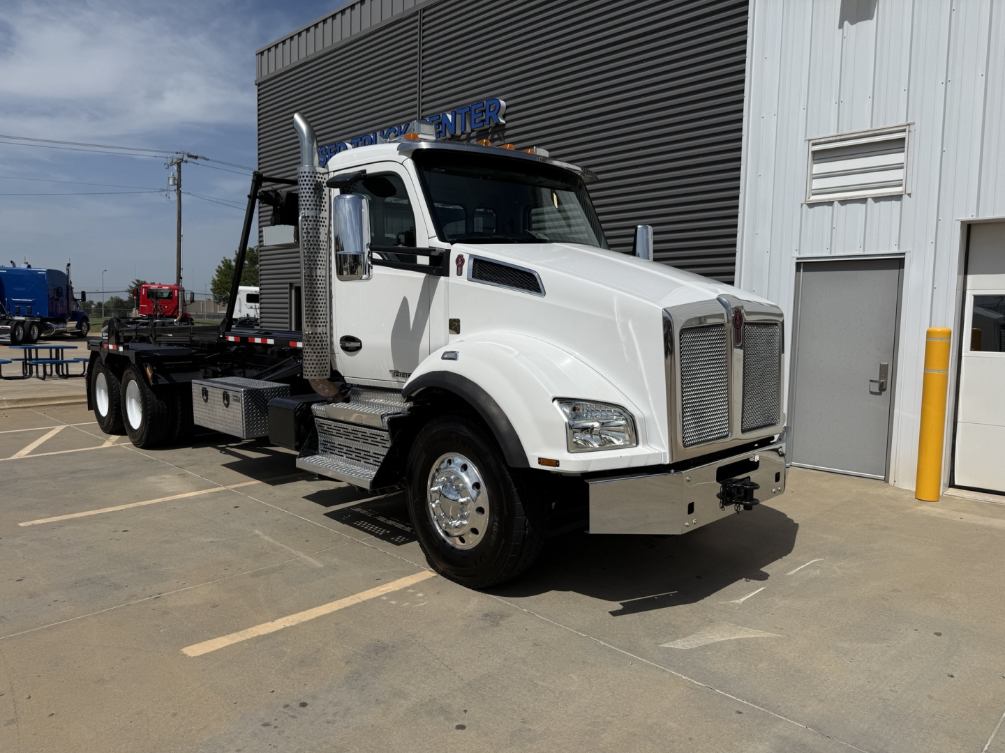 Kenworth T880 rolloff truck in white showing front and side view with chrome grille and flatbed