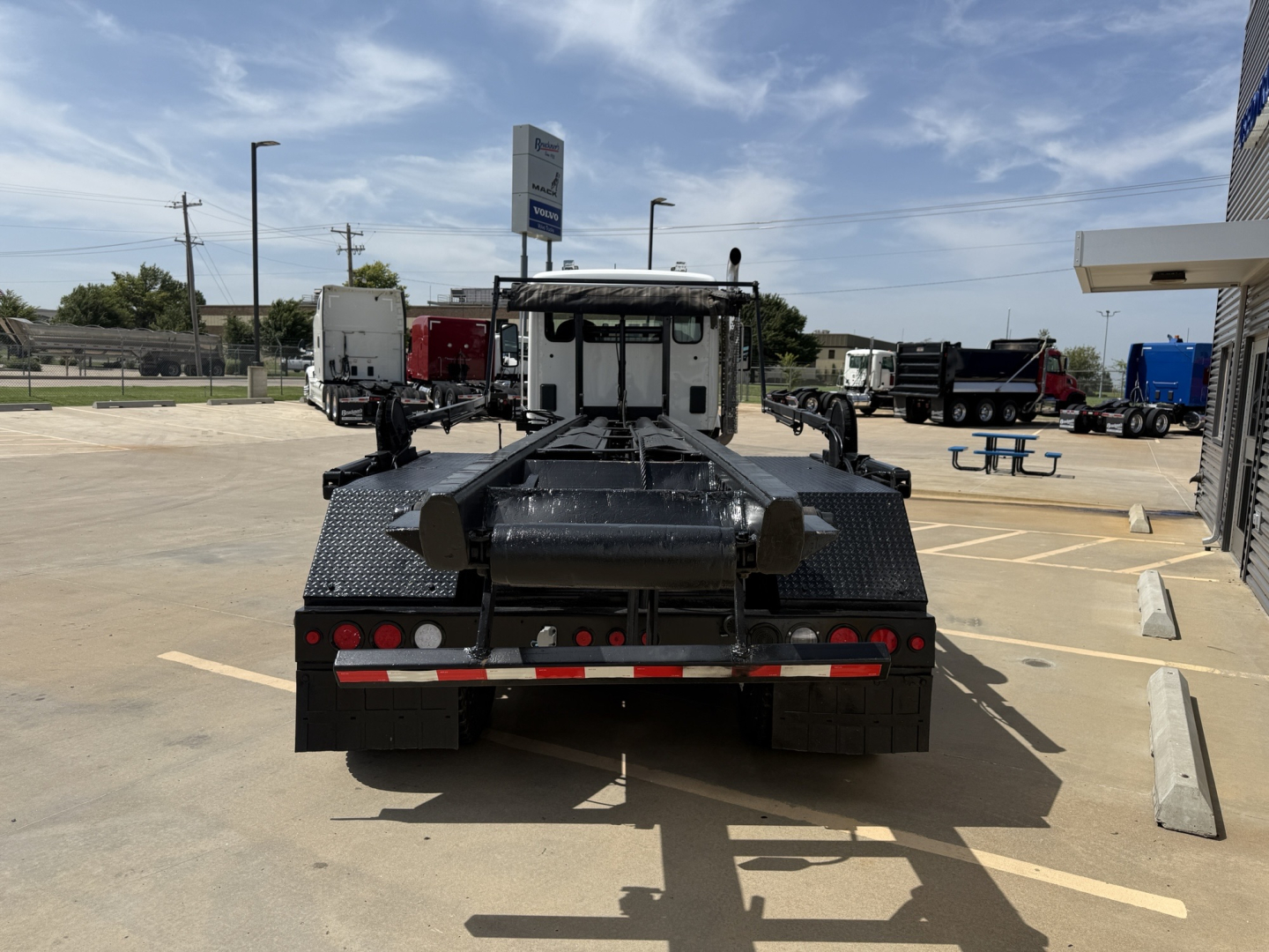 Kenworth T880 rolloff truck rear view showing flatbed/undercarriage and rear lights.